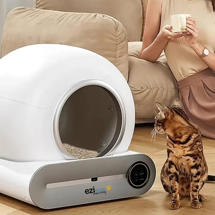 Petify litière automatique connectée semi-fermée pour chat, design moderne blanc et gris, avec un chat tigré à côté.
